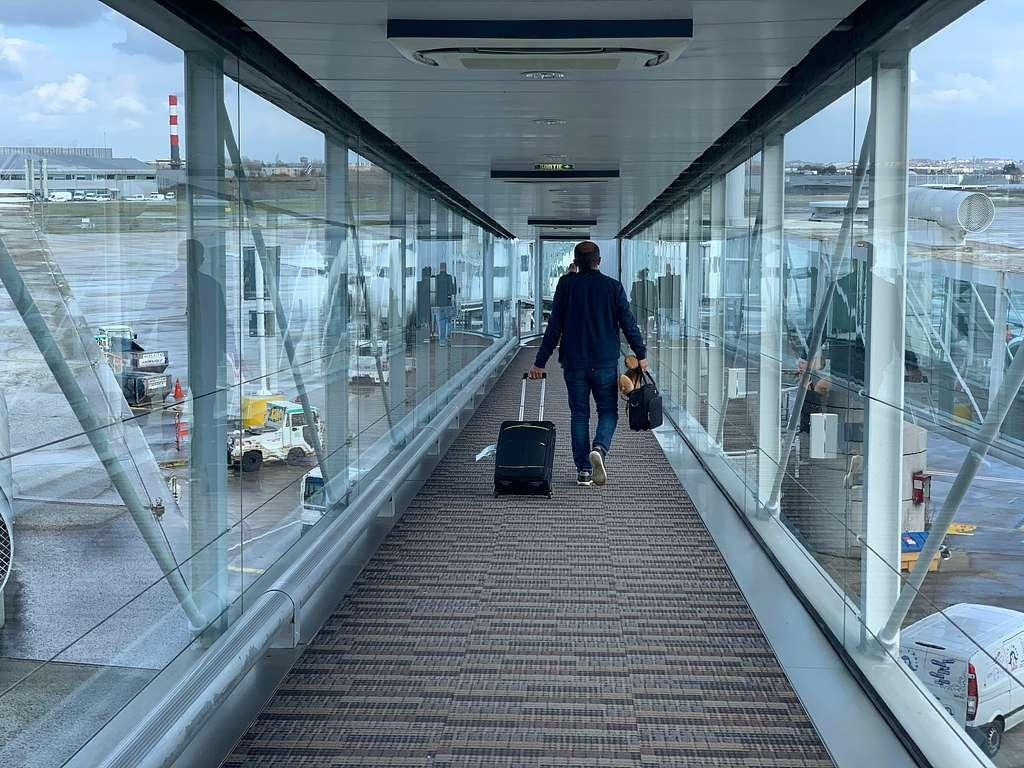 Traveler exiting Charles de Gaulle Airport with luggage.